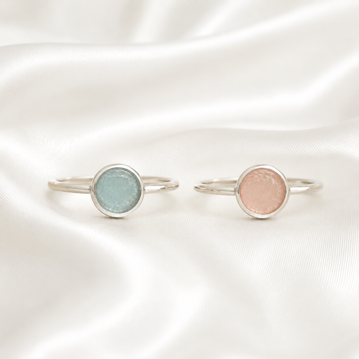 Silver round ring settings with blue and pink resin on white satin