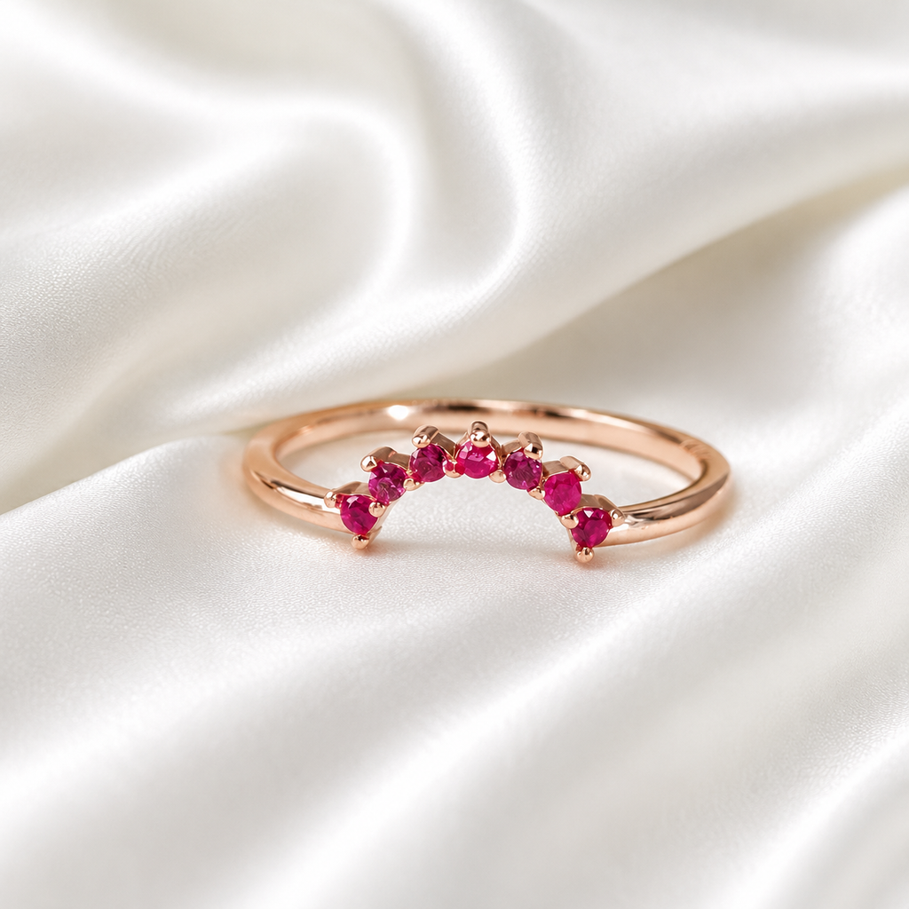 Rose gold curved crown stacker ring with ruby red crystals on white satin