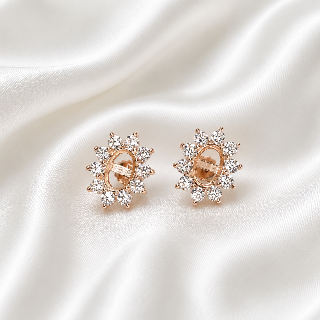 Rose gold starburst halo oval earring settings showing open bezel with prong-set CZ surround on white satin