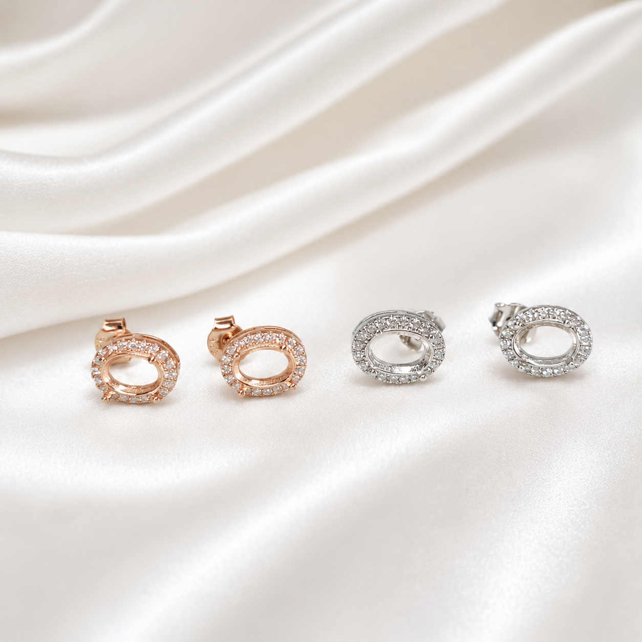 Close-up of rose gold halo oval stud earring settings showing open bezel and CZ surround on white satin