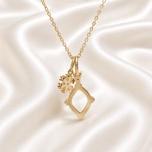 Gold diamond shape vintage necklace setting with snowflake charm on white satin - back view