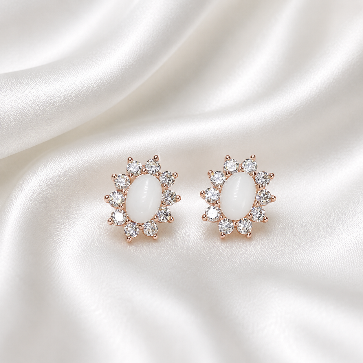 Rose gold starburst halo oval earring settings filled with white milk resin on white satin