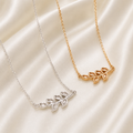 925 sterling silver and gold birthstone leaf necklaces with open marquise bezels on cream satin